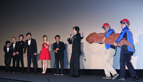 ツチノコを捕獲し隊員が小脇に抱えて檀上に