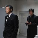 三浦友和（松岡勝俊 役）と佐藤浩市（三上義信 役）が男子トイレで、映画『64-ロクヨン-前編』（瀬々敬久監督）より