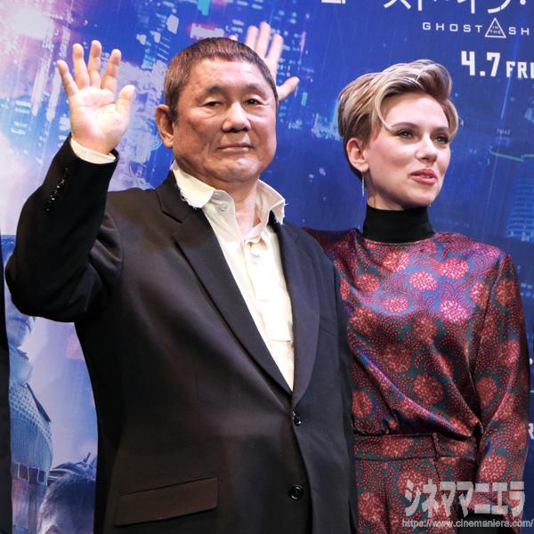 しかと手を振るビートたけしと、それを真似て控えめに手を振るスカーレット・ヨハンソン