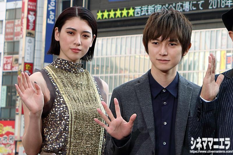 手を振る三吉彩花と本郷奏多、新宿ユニカビジョンをバックに